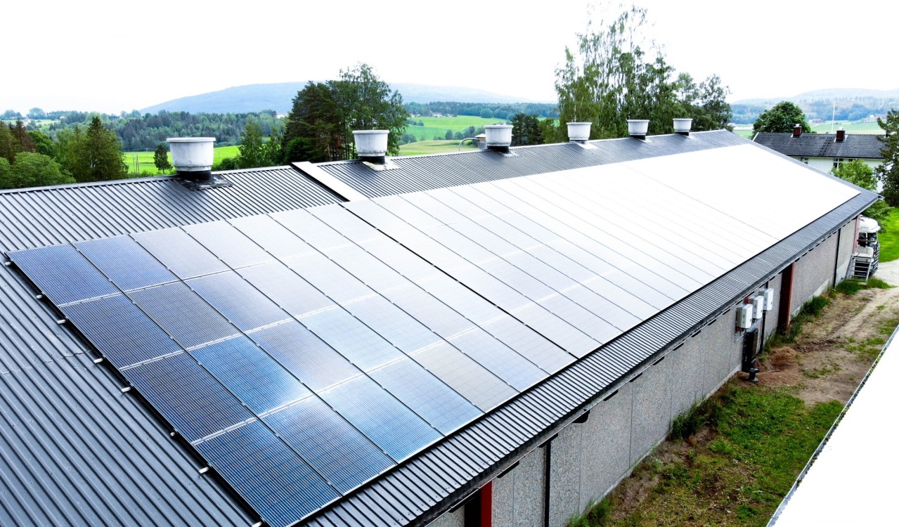 Stor landbruksbygning med solcellepanel på taket i landlige omgivelser. En viktig del av innholdet i NEK 400.