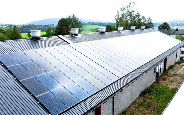 Stor landbruksbygning med solcellepanel på taket i landlige omgivelser. En viktig del av innholdet i NEK 400.
