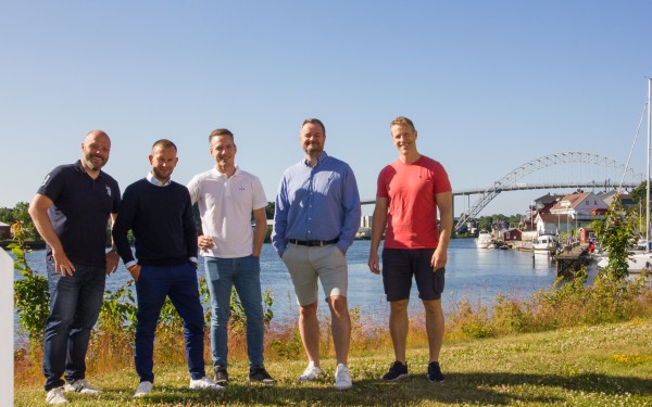 Fem ansatte i VIX står i solen ved Glomma og Fredrikstad i bakgrunnen.