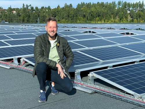 Magnus Boge i Berggård Amundsen smiler foran et stort solcelleanlegg på tak.