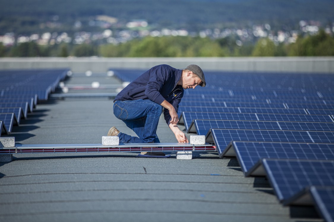 Elling Ramstad sikrer solcellepanelene i et anlegg på næringstak.